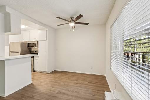 A room with a ceiling fan and a window with blinds.