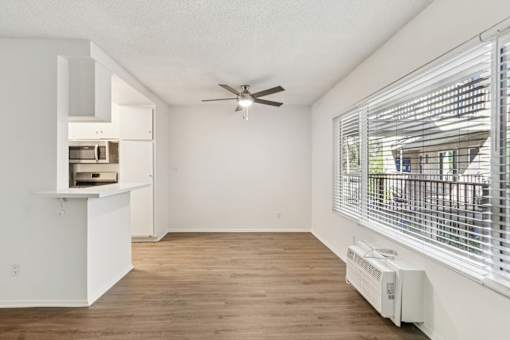 A room with a ceiling fan and a window with blinds.