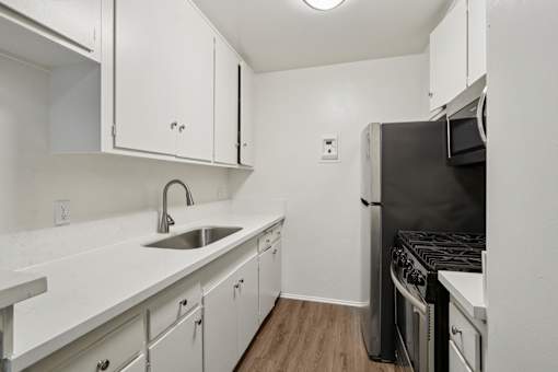 A kitchen with white cabinets and a black stove.