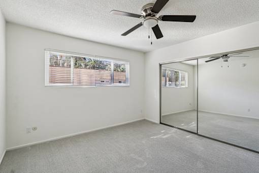 A room with a ceiling fan and a glass door.