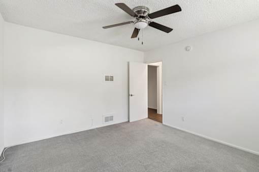 A room with a ceiling fan and carpeted floor.