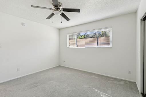 A room with a ceiling fan and a window with blinds.