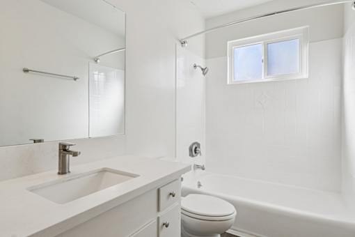 A white bathroom with a sink, toilet, and bathtub.