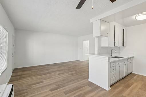 A kitchen with white cabinets and a wooden floor.
