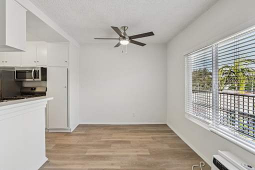 A room with a ceiling fan and a window with blinds.