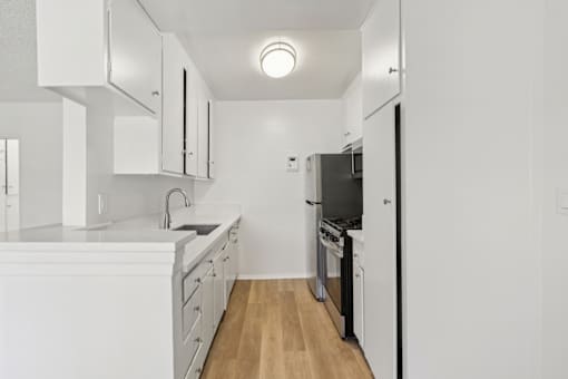 A kitchen with white cabinets and appliances.