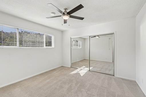 A room with a ceiling fan and a sliding glass door.