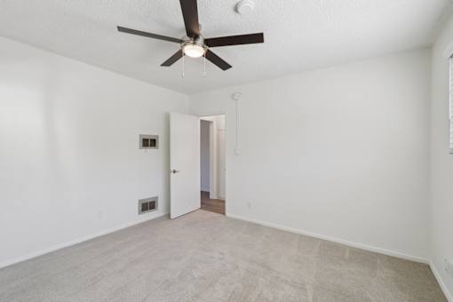 A room with a ceiling fan and carpeted floor.