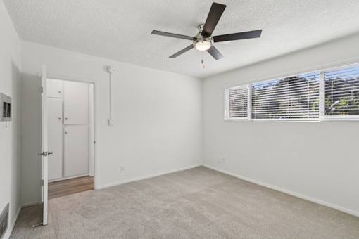 A room with a ceiling fan and a window with blinds.