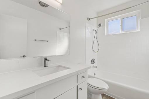 A white bathroom with a toilet, sink, and bathtub.