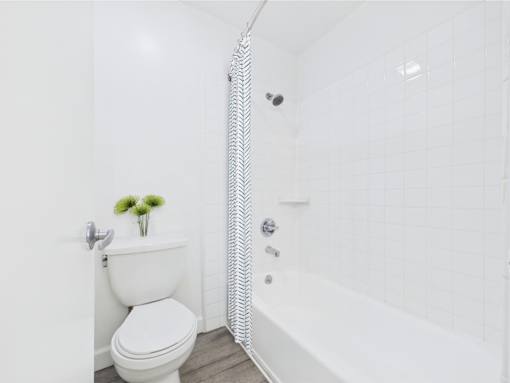 A white toilet with a white bathtub and a white shower curtain.