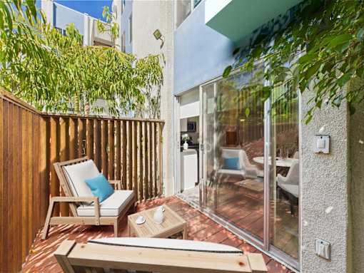 A wooden chair with a blue pillow sits on a patio.