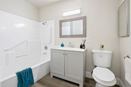 a bathroom with a white bathtub and a white toilet next to a sink with a mirror
