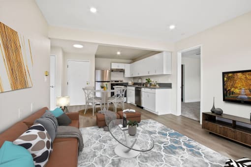 a living room with a couch a table and a chair and a kitchen in the background