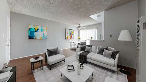 A modern living room with a white couch and a painting on the wall.