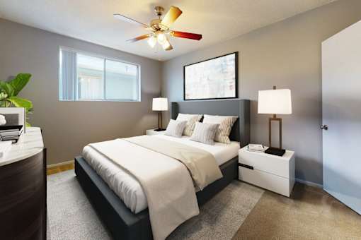 A bedroom with a large bed, a ceiling fan, and two lamps.