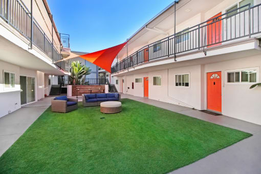 the courtyard of a building with a lawn and a red door