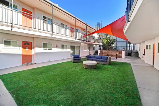 the courtyard of a building with green grass and furniture