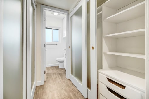 a walk in closet with a door to a bathroom with a toilet