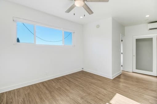 an empty living room with white walls and a wooden floor
