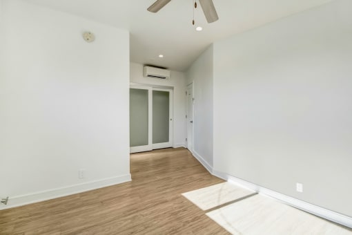 a living room with white walls and wood flooring and a ceiling fan