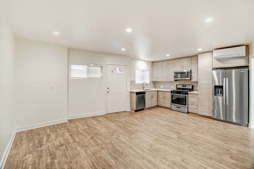 an empty kitchen with stainless steel appliances and a wooden floor