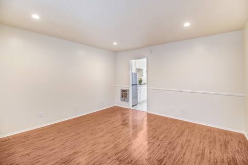 A room with wooden flooring and white walls.