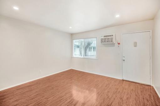 Empty room with wood flooring and white walls.