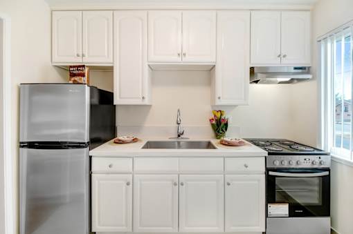 A kitchen with white cabinets and a black refrigerator.