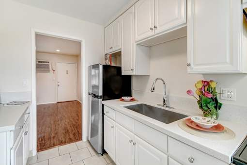 A kitchen with white cabinets and a black refrigerator.