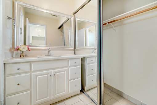 A white bathroom vanity with a mirror above it.