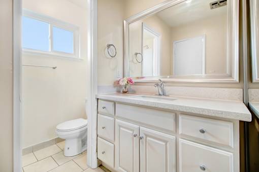A white bathroom with a toilet, sink, and mirror.