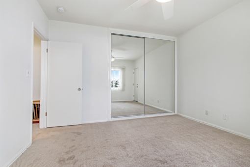 an empty living room with a mirror in the middle of it