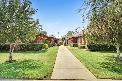 a sidewalk in front of houses with grass and trees