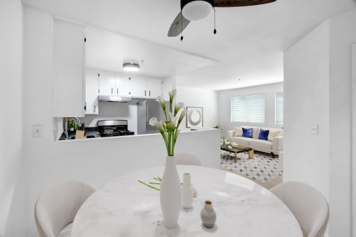 a white kitchen and dining room with a white table