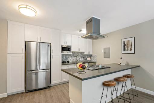 Kitchen with stainless steel French door fridge, microwave and breakfast bar with an electric top stove and range hood