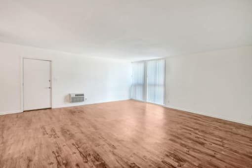 an empty living room with wood floors and white walls
