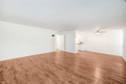 an empty living room with wood floors and white walls