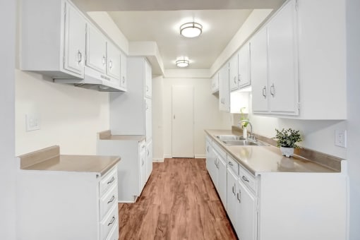 a large white kitchen with white cabinets and a wood floor