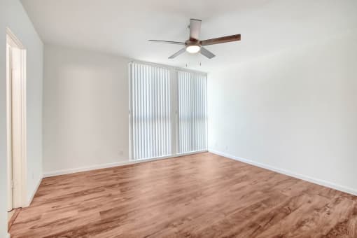 an empty living room with wood flooring and a ceiling fan