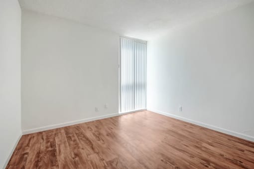 the living room of an apartment with wood flooring and white walls