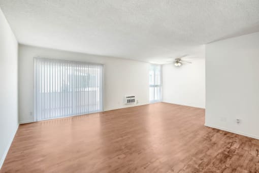 an empty living room with wood flooring and a ceiling fan