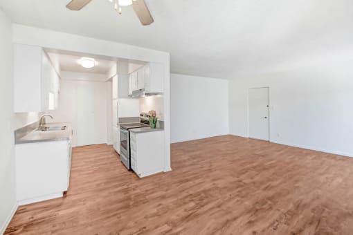 an empty living room and kitchen with a wood floor