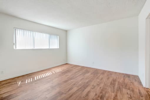 the spacious living room with wood flooring and a window