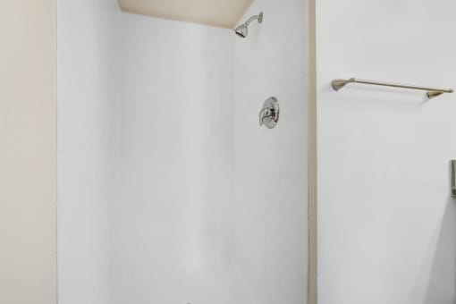 a white bathroom with a shower and a towel rack