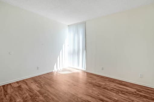 an empty living room with wood flooring and a window