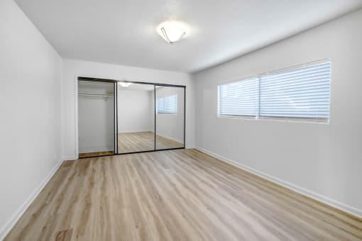 an empty living room with a mirrored closet and a window