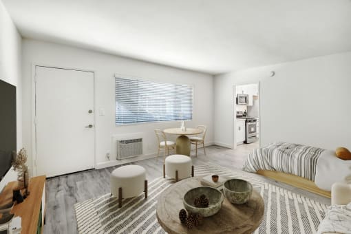 a living room with a bed and a desk and a table and chairs