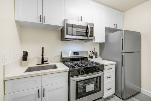 an apartment kitchen with stainless steel appliances and white cabinets