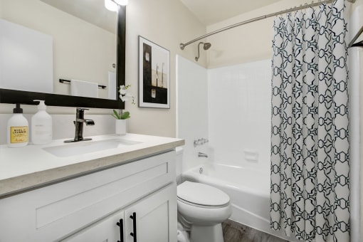 a white bathroom with a black and white shower curtain
